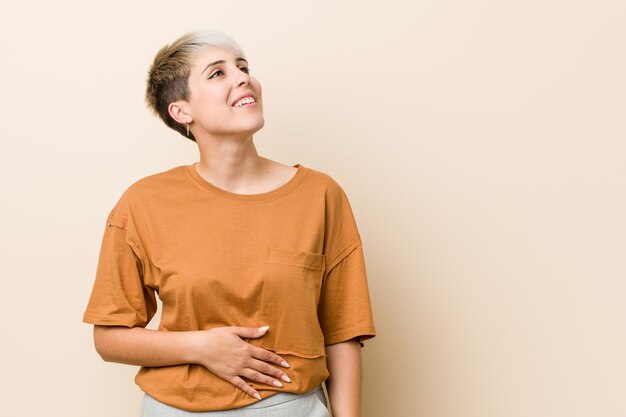 Jeune femme de taille plus aux cheveux courts touche le ventre, sourit doucement, manger et concept de satisfaction.