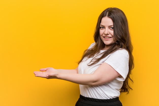 Jeune femme de taille plus galbée tenant un espace de copie sur une paume.