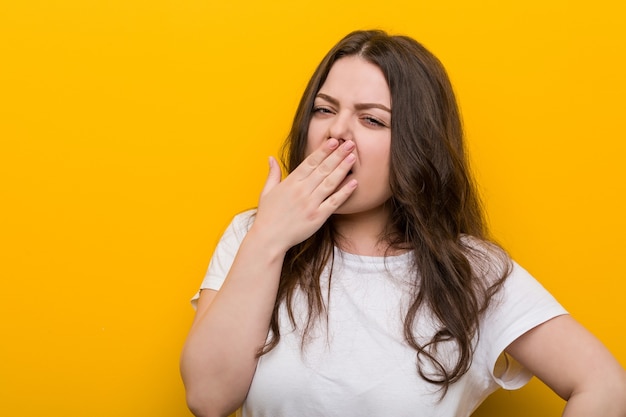 Jeune femme de taille plus sinueuse le bâillement montrant un geste fatigué couvrant la bouche avec lui la main.