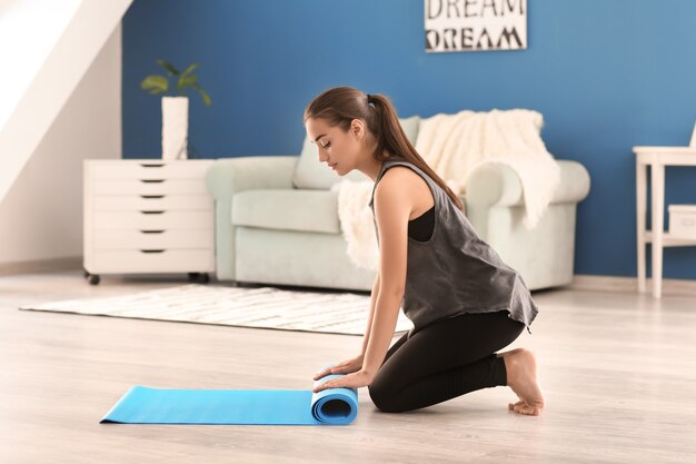 Jeune femme avec tapis de yoga à l'intérieur