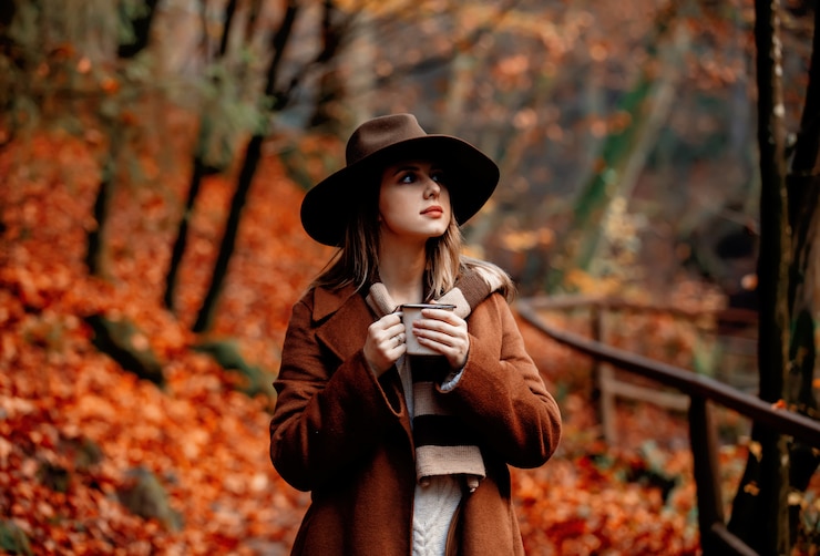 Photo jeune femme avec une tasse de café dans un parc de la saison d'automne