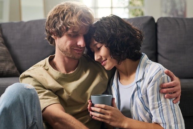 Jeune femme avec une tasse de café en gardant la tête sur l'épaule de son mari