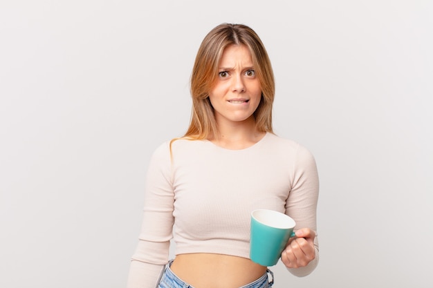 Jeune femme avec une tasse de café à perplexe et confus