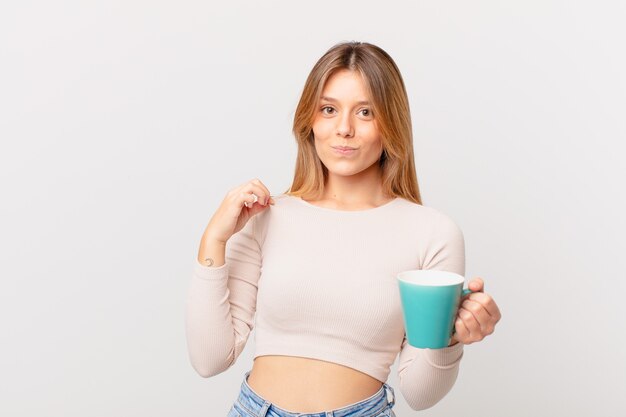 Jeune femme avec une tasse de café semblant arrogante, réussie, positive et fière