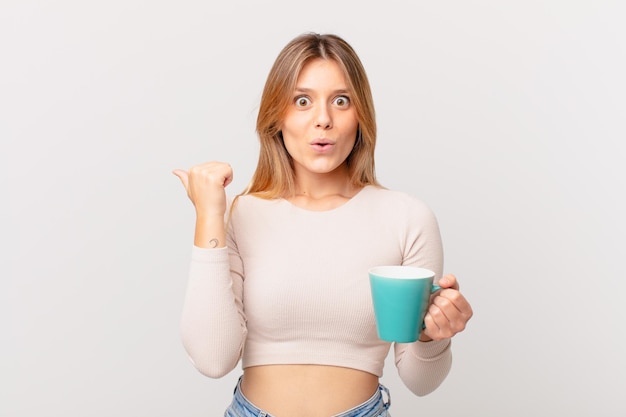 Jeune femme avec une tasse de café à la stupéfaction de l'incrédulité