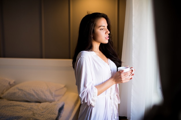 Jeune femme avec une tasse dans la chambre