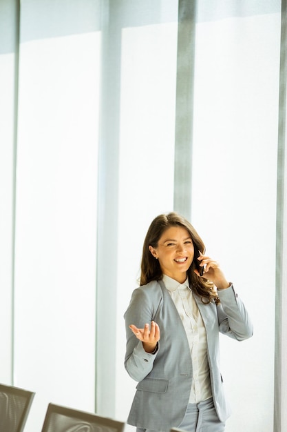 Jeune femme avec un téléphone portable à la fenêtre