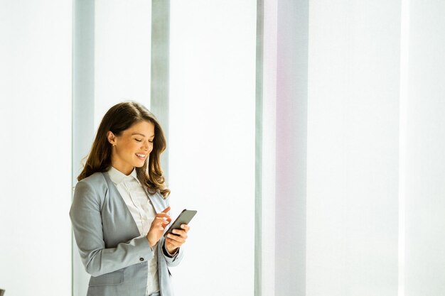 Jeune femme avec un téléphone portable à la fenêtre