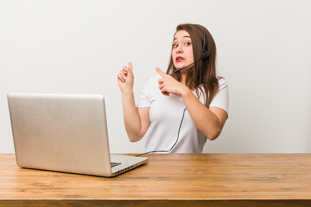 Jeune femme télévendeur choqué pointant avec des index vers un espace de copie.