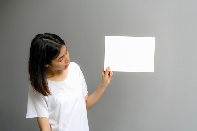 Jeune femme tenant une affiche vierge pour texte sur fond blanc.