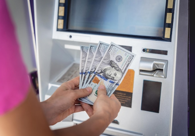 Photo une jeune femme tenant de l'argent dans ses mains après avoir retiré l'argent au guichet automatique