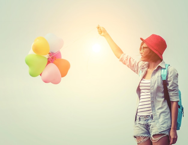 Photo une jeune femme tenant des ballons colorés contre le ciel au coucher du soleil