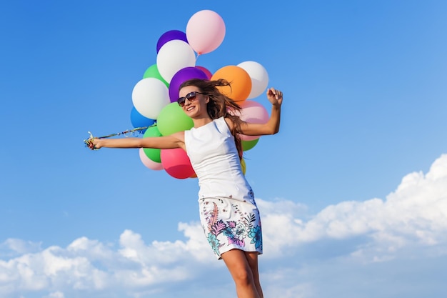 Jeune femme tenant des ballons sautant sur le terrain aux beaux jours