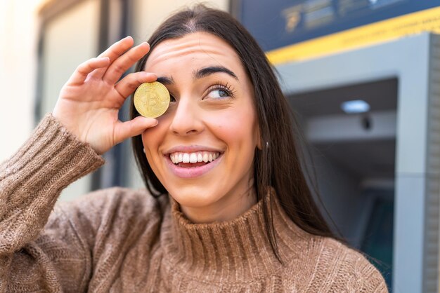 Jeune femme tenant un Bitcoin à l'extérieur