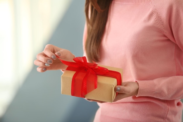 Jeune femme tenant une boîte-cadeau à la maison gros plan