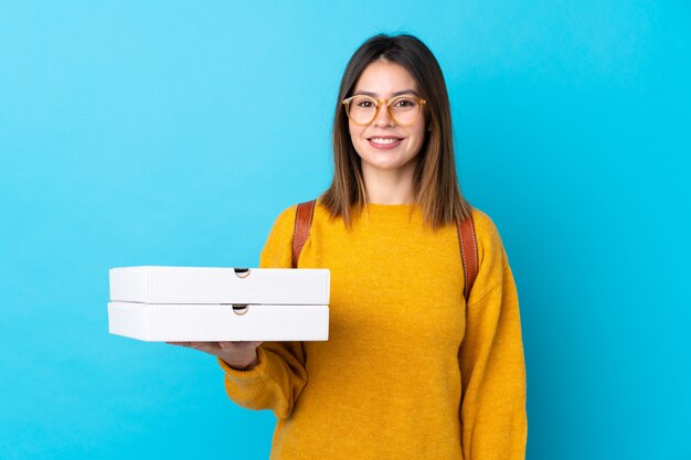 Jeune femme tenant une boîte à pizza sur un mur bleu isolé