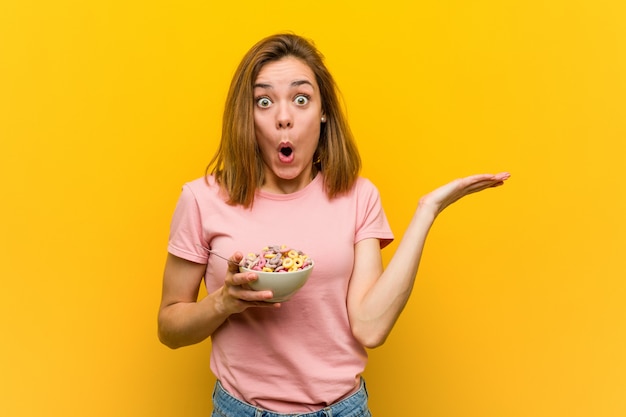 Jeune femme tenant un bol de céréales impressionné