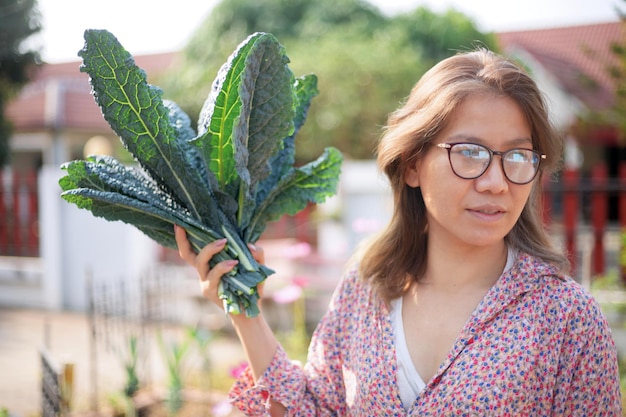 Photo une jeune femme tenant un bouquet de chou vert de son jardin de légumes cultivés à la maison