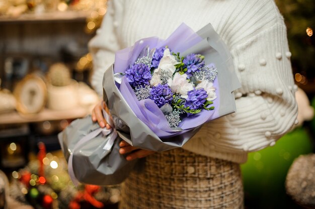 Jeune femme tenant un bouquet de jacinthe bleue avec des fleurs blanches et des branches d'argent