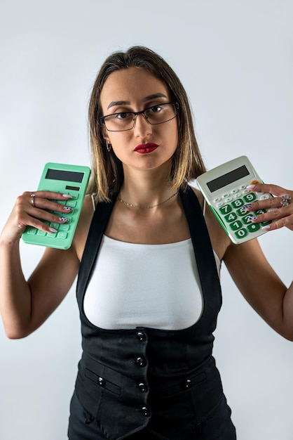 Jeune femme tenant une calculatrice et souriant ou se demandant isolé sur fond bleu