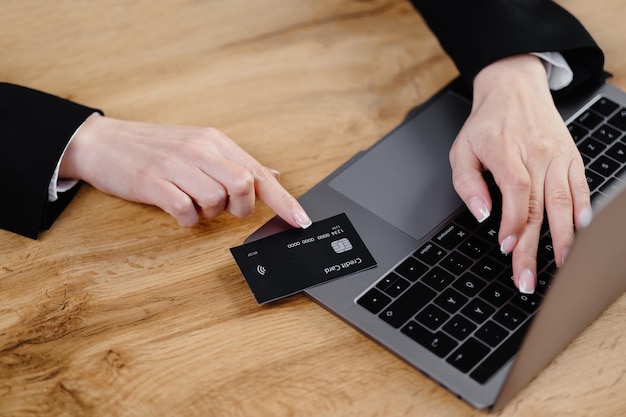 Jeune femme tenant une carte de crédit et à l'aide d'un ordinateur portable