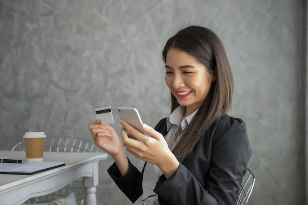 Jeune femme tenant la carte de crédit, magasinage en ligne de l&#39;ordinateur portable.