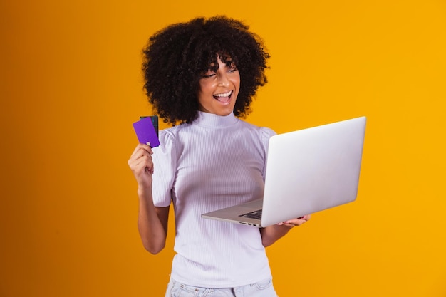 Jeune femme tenant une carte de crédit et utilisant un ordinateur portable. Notion de magasinage en ligne