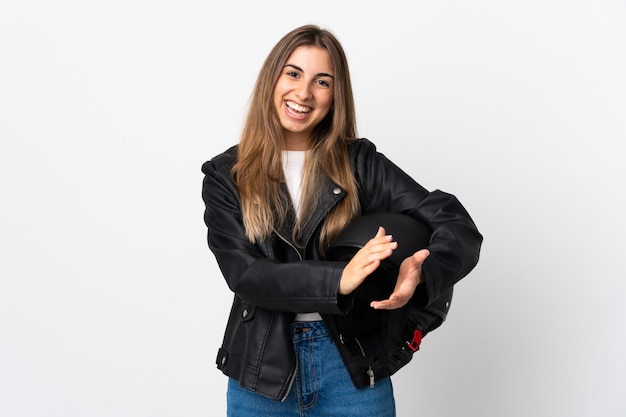 Jeune femme tenant un casque de moto sur un mur blanc isolé applaudissant