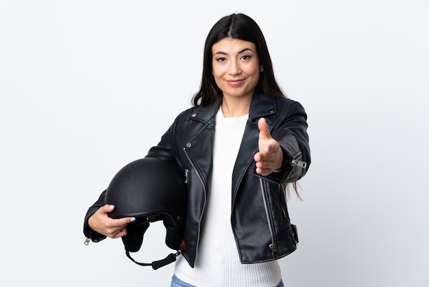 Jeune femme tenant un casque de moto sur un mur blanc isolé poignée de main après une bonne affaire