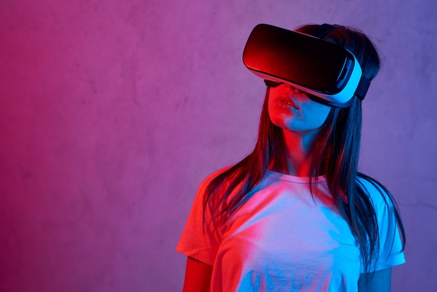 Jeune femme tenant un casque de réalité virtuelle tout en portant un t-shirt blanc