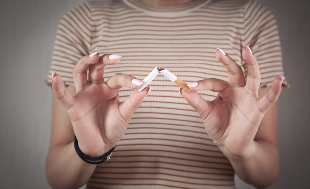 Photo jeune femme tenant une cigarette cassée. arrêter de fumer