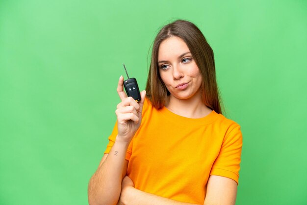 Jeune femme tenant des clés de voiture sur fond de clé chroma isolé avec une expression triste