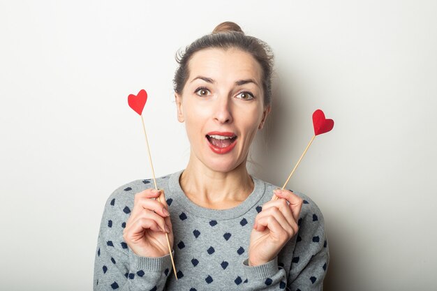 Jeune femme tenant des coeurs sur des bâtons sur un fond clair. Saint Valentin, anniversaire. Bannière.