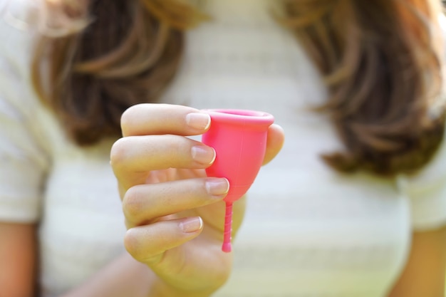 Jeune femme tenant la coupe menstruelle. Produit alternatif d'hygiène féminine au lieu du tampon pendant les règles.