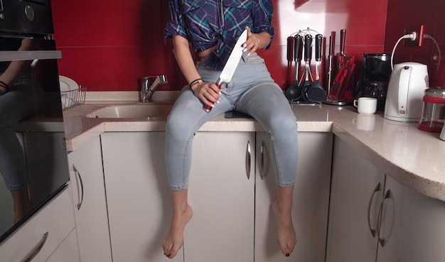 Jeune femme tenant un couteau de cuisine.