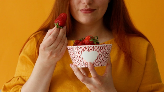 Jeune femme tenant dans les mains et donne des aliments sains frais de grandes fraises juteuses