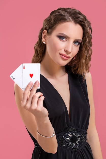 Photo jeune femme tenant deux as à la main contre sur fond rose