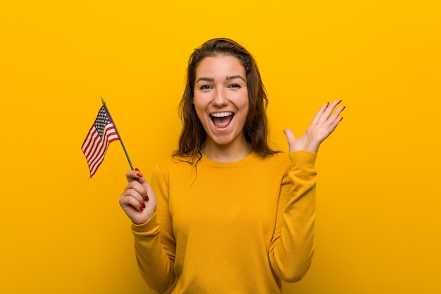 Jeune femme tenant un drapeau des États-Unis célébrant une victoire ou un succès