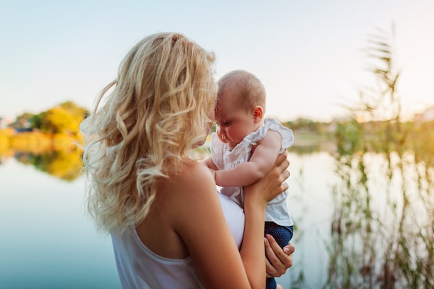 Jeune femme tenant et embrassant la petite fille de la rivière Spring. Famille marchant à l'extérieur. Enfant explorant le monde