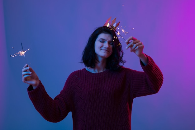 Jeune femme tenant des étincelles de Noël festives en mains.