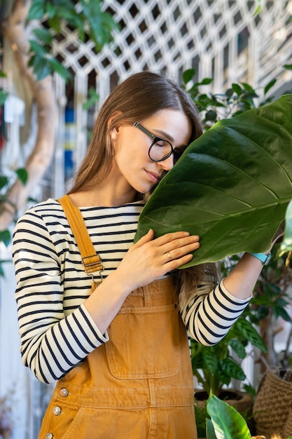 Jeune femme tenant une feuille verte relaxante après le travail dans une serre ou un jardin de maison