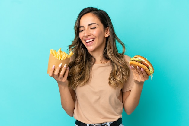 Jeune femme tenant des frites et burger sur fond isolé