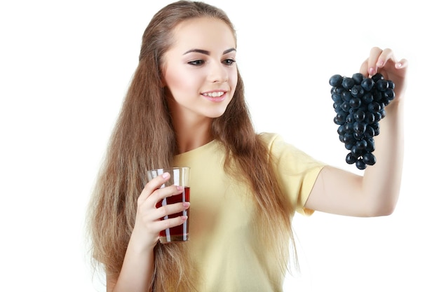 Jeune femme tenant une grappe de raisin et un verre de jus