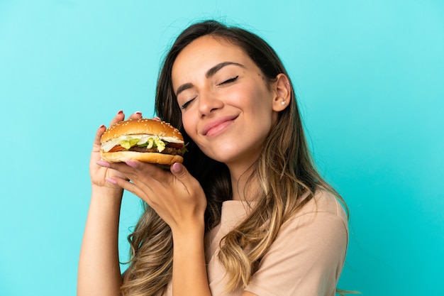 Jeune femme tenant un hamburger sur fond isolé