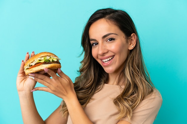 Jeune femme tenant un hamburger sur fond isolé