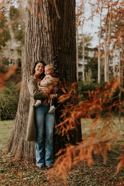 Une jeune femme tenant une jolie petite fille dans le parc d'automne