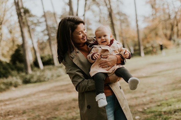 Une jeune femme tenant une jolie petite fille dans le parc d'automne