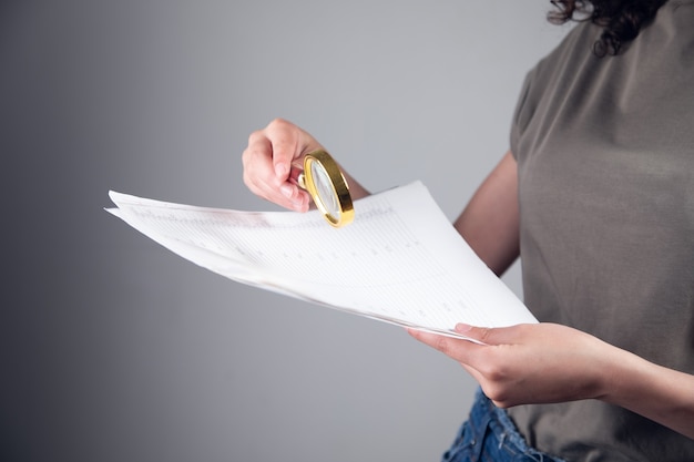 Jeune femme tenant une loupe et un document