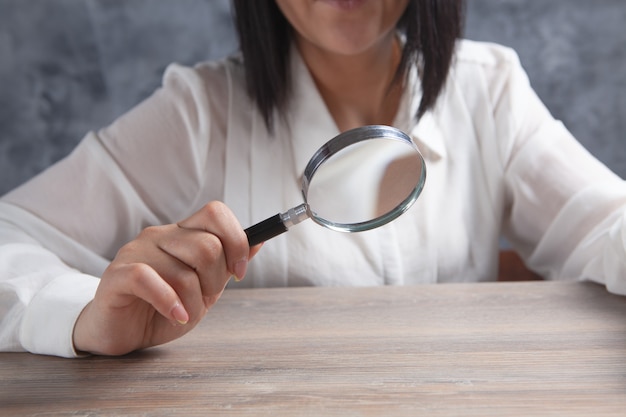 Jeune femme tenant une loupe près de la table