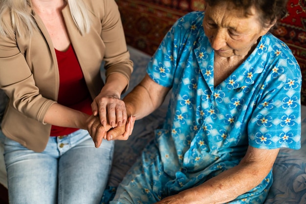 Jeune femme tenant la main d'une femme âgée